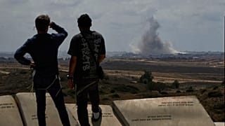 Des personnes regardent la fumée s'élever dans le ciel après une explosion dans la bande de Gaza alors qu'elles visitent un site touristique à Sderot, dans le sud d'Israël, le jeudi 22 mai 2025.