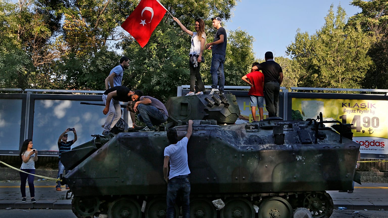 Vatandaşlar, Ankara'daki askeri karargaha yakın bir sokakta protestocular tarafından saldırıya uğrayan hasarlı bir tankın üstünde