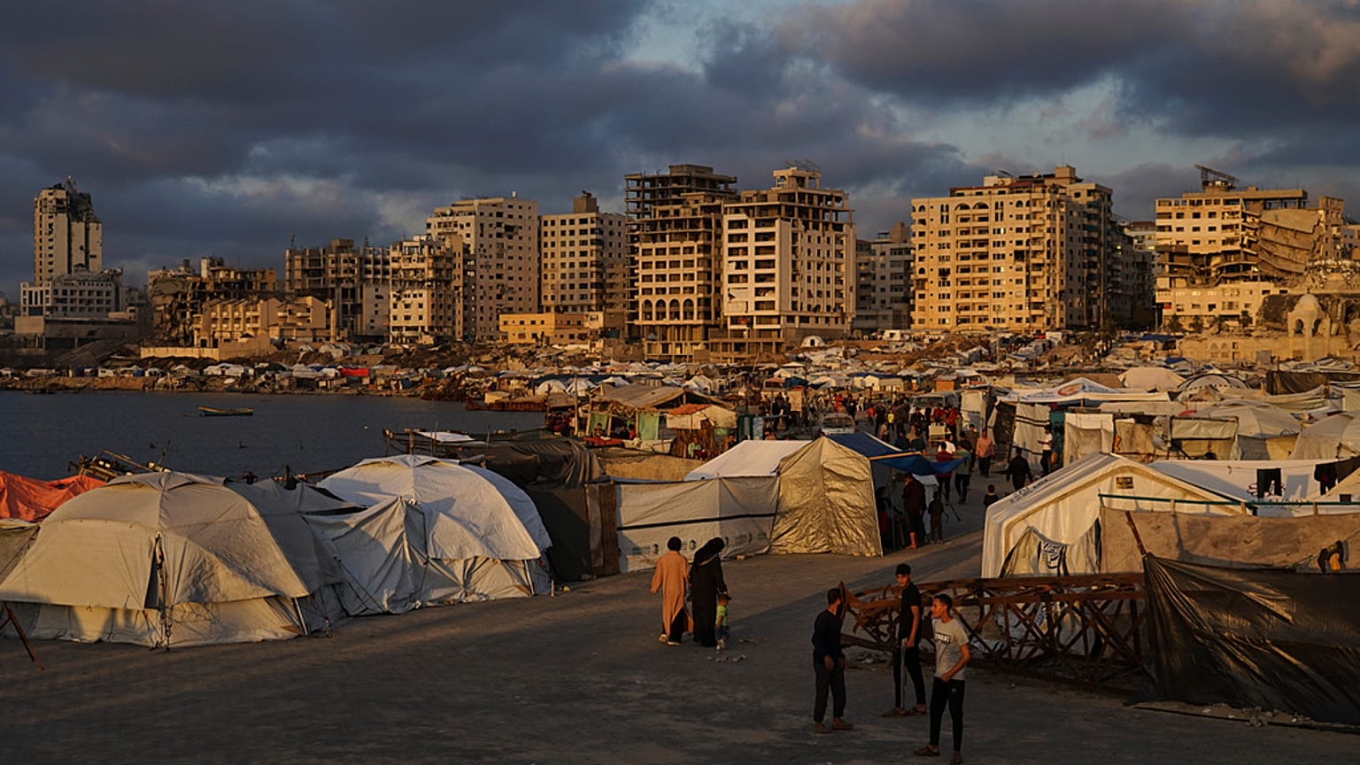 نازحون فلسطينيون يمشون في مخيم مؤقت في ميناء مدينة غزة يوم الخميس 22 أيار / مايو 2025. 
