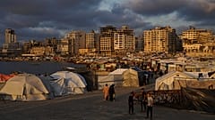 نازحون فلسطينيون يمشون في مخيم مؤقت في ميناء مدينة غزة يوم الخميس 22 أيار / مايو 2025. 