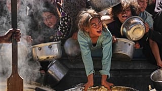 فلسطينيون يحاولون الحصول على طعام تبرّعت به جهات خيرية في مطبخ جماعي بخان يونس، جنوب قطاع غزة، الجمعة 16 أيار/مايو 2025 