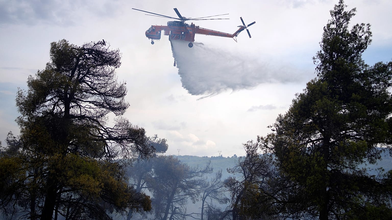 Yunanistan'ın başkenti Atina'nın kuzeyindeki Stamata banliyösünde çıkan orman yangını sırasında bir helikopter ormanlık alana su bırakıyor, 4 Eylül 2023. 