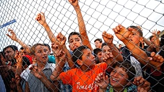 Crianças refugiadas sírias atrás de uma vedação no campo de refugiados de Nizip, na província de Gaziantep, no sudeste da Turquia.