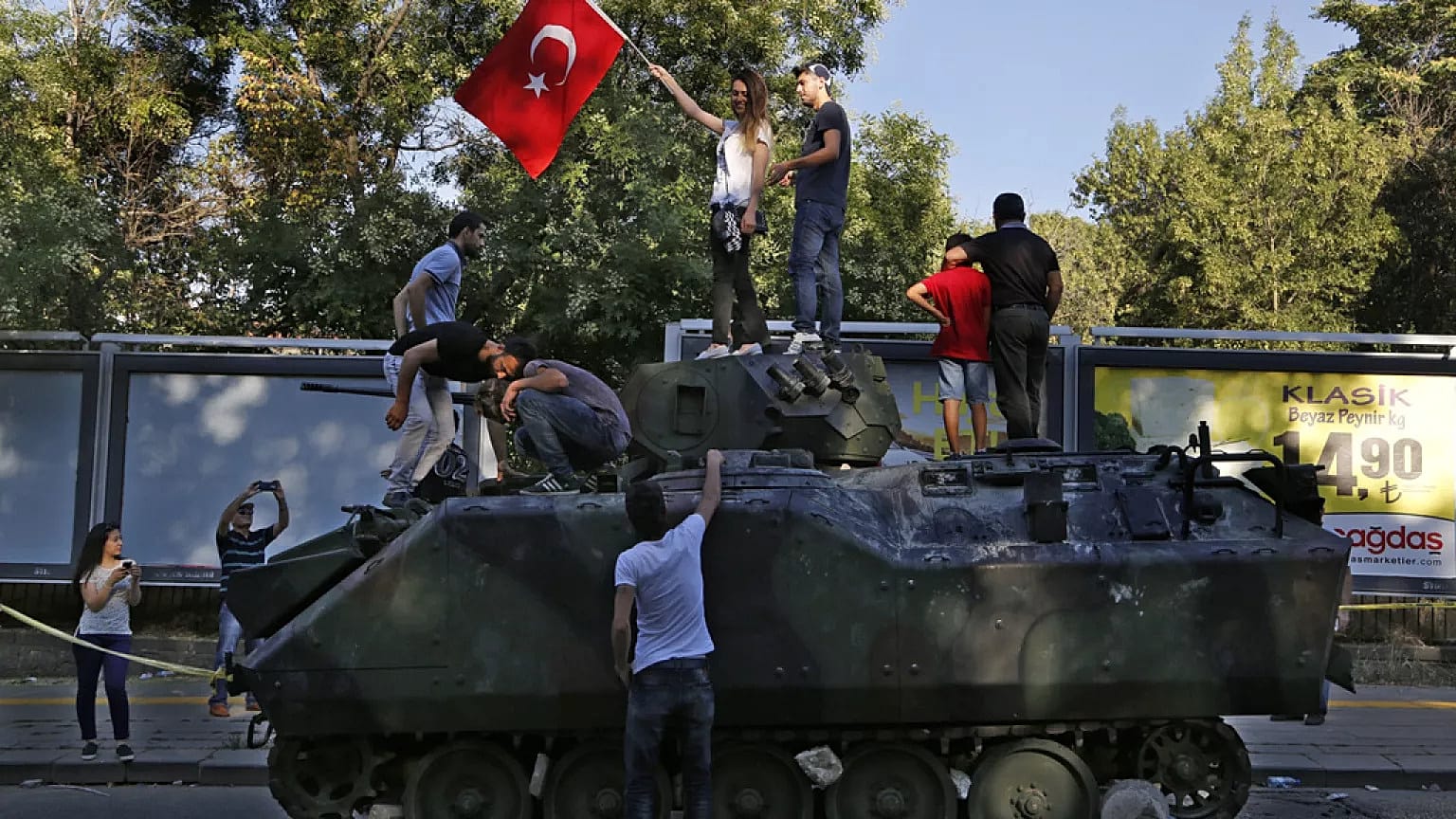 Vatandaşlar, Ankara'daki askeri karargaha yakın bir sokakta protestocular tarafından saldırıya uğrayan hasarlı bir tankın üstünde