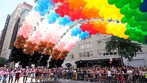 Rainbow balloons are carried down the parade route a NYC Pride March.