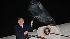 El presidente Donald Trump tiene un problema con su paraguas mientras embarca en el Air Force One