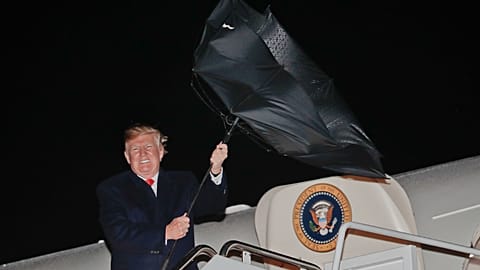 President Donald Trump having an issue with his umbrella while embarking on Air Force One