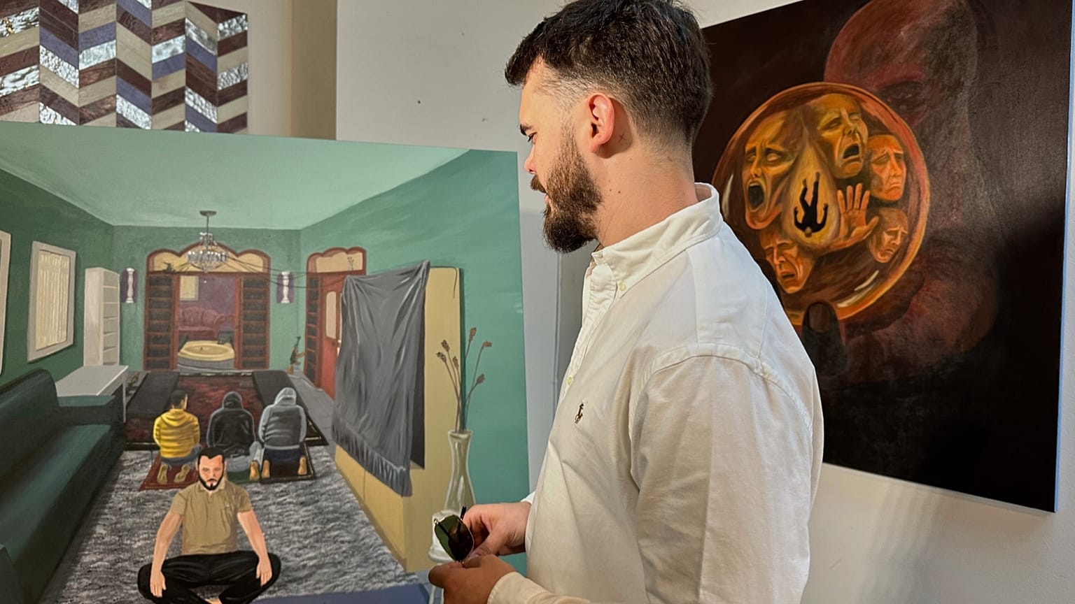 Andrei Kozlov, who was taken hostage by Hamas during the 7 October 2023, attack on Israel, looks at his painting, “One God,”