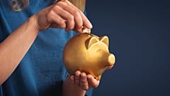 Eine Frau steckt eine Münze in ein Sparschwein. 