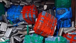 Sacos e narcóticos embrulhados em plástico são esvaziados de um contentor no porto de Antuérpia, 2021