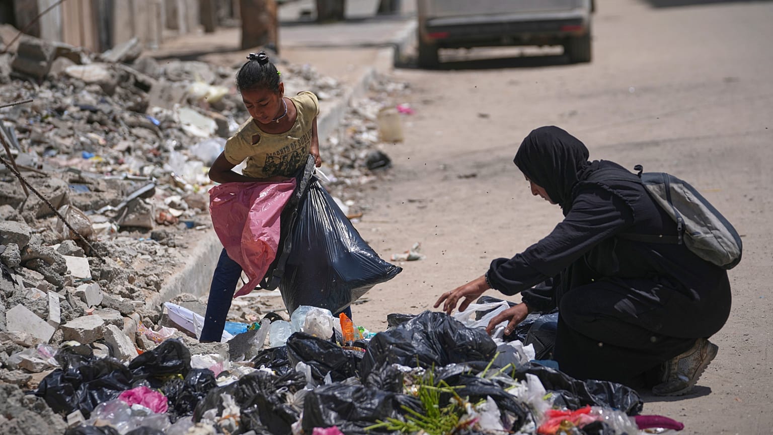 Islam Abu Taeima, 40-letnia matka pięciorga dzieci, oraz jej 9-letnia córka Waed szukają jedzenia w stosie śmieci w Gazie, niedziela, 25 maja 2025 roku