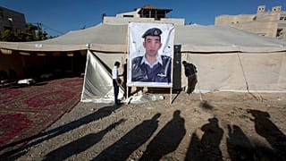  يرفع عمال لافتة تحمل صورة الطيار الأردني الملازم معاذ الكساسبة، الذي قتل على يد تنظيم الدولة الإسلامية، أمام خيمة للمؤيدين في عمّان، الأردن