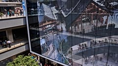 İnsanlar 26 Mayıs 2025, Pazartesi günü Pekin'de yeni açılan Hutong tarzı açık hava alışveriş merkezini tanıtan bir projektör ekranının önünde tur atıyor.
