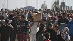 Palestinesi trasportano scatole di aiuti umanitari consegnati dalla Gaza humanitarian foundation a Rafah, nel sud della Striscia di Gaza, 27 maggio 2025
