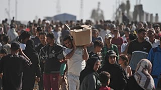 Palestinesi trasportano scatole di aiuti umanitari consegnati dalla Gaza humanitarian foundation a Rafah, nel sud della Striscia di Gaza, 27 maggio 2025