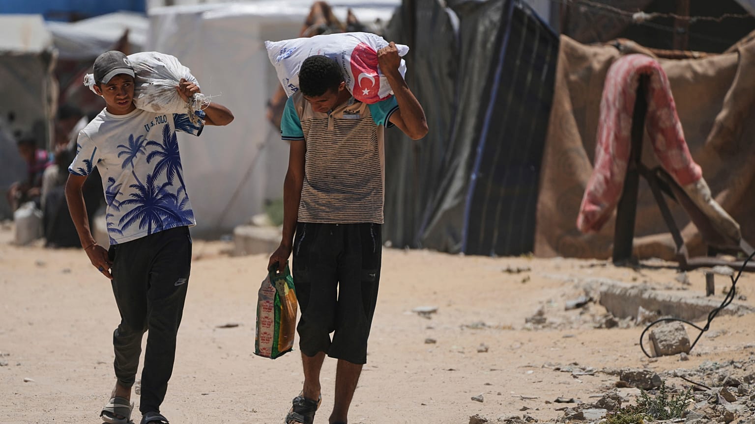 يحمل الفلسطينيون الطعام والمساعدات الإنسانية أثناء وصولهم إلى خان يونس، جنوب قطاع غزة، يوم الأربعاء، 28 مايو 2025