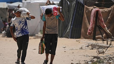 Palestinians carry food and humanitarian aid as they arrive in Khan Younis, southern Gaza Strip, on Wednesday, May 28, 2025. 