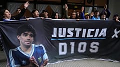 ARCHIVO: Fanáticos del fallecido astro del fútbol Diego Maradona sostienen una pancarta que dice en español "Justicia por Dios" afuera del tribunal en San Isidro, Argentina, 11 de marzo de 2025.