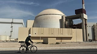 Un operaio va in bicicletta davanti all'edificio del reattore della centrale nucleare di Bushehr, 26 ottobre 2010.