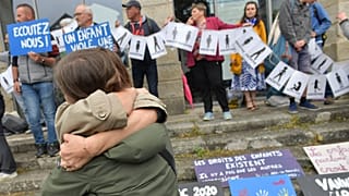 Protestocular, Vannes'da cinsel saldırı mağdurlarını temsil eden bir pankart tutarken insanlar kucaklaşıyor, 28 Mayıs 2025 