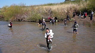 Famílias sírias alauítas atravessam um rio que marca a fronteira entre a Síria e o Líbano na província de Akkar, 11 de março de 2025