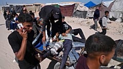 فلسطينيون يحملون رجلًا مصابًا بعد إطلاق النار عليه في مركز لتوزيع المساعدات تديره مؤسسة غزة الإنسانية في خان يونس  29 مايو/أيار 2025. 