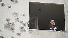 Eine Frau schaut durch das Fenster ihrer beschädigten Wohnung nach einem russischen Angriff in Charkiw, 18. April 2025