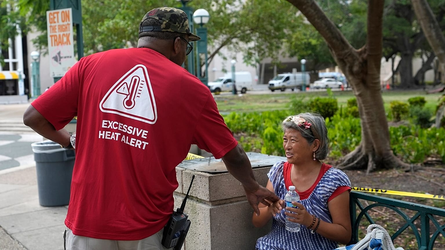 Ricky Leath, un especialista en divulgación de la ciudad de Miami, habla con Bei Zhao, a la derecha, mientras trabaja con el Miami-Dade County Homeless Trust para distribuir botellas de agua.