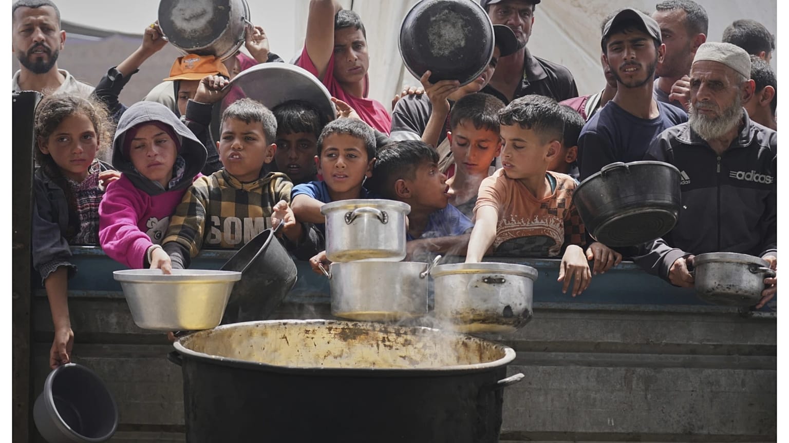 أطفال فلسطينيون ينتظرون الحصول على الطعام من مطبخ مجتمعي في خان يونس، جنوب قطاع غزة، يوم الخميس 24 أبريل 2025