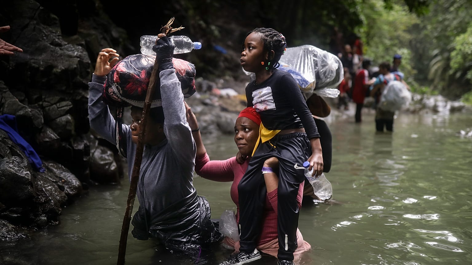 Migrantes haitianos vadean el agua mientras cruzan el Paso del Darién de Colombia a Panamá con la esperanza de llegar a EE.UU., 9 de mayo de 2023.