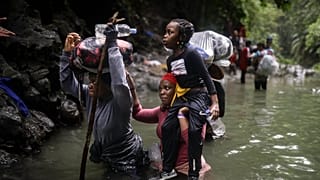 Migrantes haitianos atravessam a água enquanto cruzam o Darien Gap da Colômbia para o Panamá na esperança de chegar aos EUA, 9 de maio de 2023