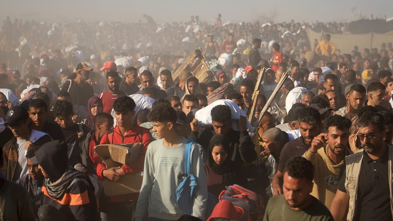 Des Palestiniens transportent des boîtes et des sacs contenant de la nourriture et de l'aide humanitaire fournie par la Fondation humanitaire de Gaza, une organisation soutenue par les États-Unis et approuvée par Israël, à Rafah, dans le sud de la bande de Gaza. 