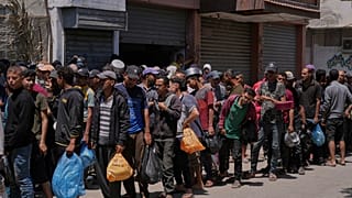 فلسطينيون يصطفون لتوزيع المواد الغذائية في دير البلح ، قطاع غزة ، الجمعة ، 30 أيار / مايو 2025.