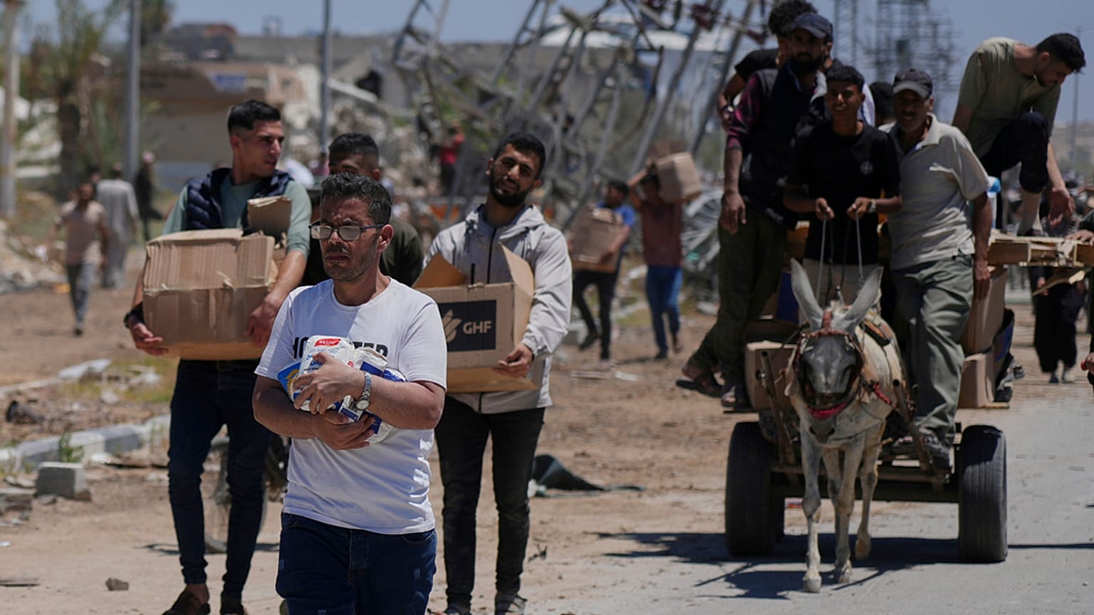 يحمل الفلسطينيون صناديق وحقائب تحتوي على مواد غذائية وطرود مساعدات إنسانية سلمتها مؤسسة غزة الإنسانية ، وهي منظمة مدعومة من الولايات المتحدة وافقت عليها إسرائيل ، في خان يونس 