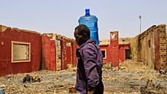 رجل يحمل حاوية مياه أمام مبنى تضرر خلال الحرب الأهلية عند نقطة توزيع بسبب انقطاع المياه في الخرطوم، السودان، الأحد 25 مايو 2025. 
