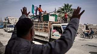  رجل يستقبل شاحنات تحمل عائلات نازحة أثناء عودتها، بدعم من منظمة غير حكومية، إلى قريتهم بعد أكثر من خمس سنوات في مخيمات أطمة بالقرب من الحدود السورية التركية، في كفر سجنة، جنو