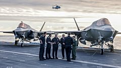 Der britische Premierminister Keir Starmer, Mitte links, und Verteidigungsminister John Healy, Mitte rechts, sprechen mit Marineoffizieren auf dem Flugdeck der HMS Prince of Wales in Plymou