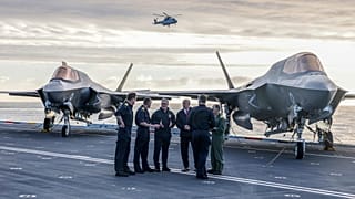 O primeiro-ministro britânico Keir Starmer, ao centro à esquerda, e o secretário da Defesa John Healy, ao centro à direita, conversam com oficiais da Marinha no convés de voo do HMS Prince of Wales em Plymou