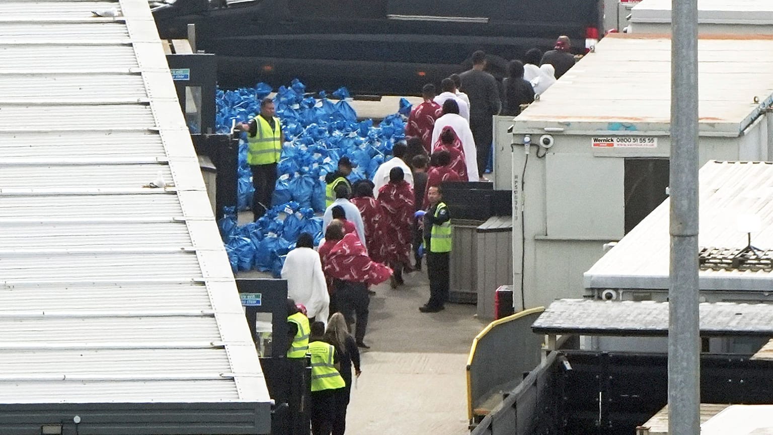 A group of people believed to be migrants are led through the Border Force compound in Dover, England, 1 June 2025.
