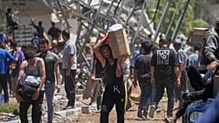 فلسطينيون يحملون صناديق وأكياسًا تحتوي على مساعدات غذائية وإنسانية قدمتها مؤسسة غزة الإنسانية في خان يونس