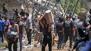 فلسطينيون يحملون صناديق وأكياسًا تحتوي على مساعدات غذائية وإنسانية قدمتها مؤسسة غزة الإنسانية في خان يونس