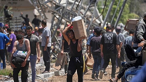 فلسطينيون يحملون صناديق وأكياسًا تحتوي على مساعدات غذائية وإنسانية قدمتها مؤسسة غزة الإنسانية في خان يونس