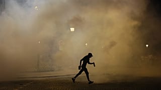 A man walks past teargas during incidents after the Champions League final soccer match between Paris Saint-Germain and Inter Milan in Paris, 1 June, 2025