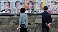 People look at posters showing candidates for the 3 June presidential election in Seoul, 2 June, 2025