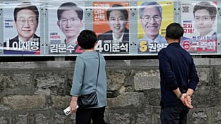 People look at posters showing candidates for the 3 June presidential election in Seoul, 2 June, 2025