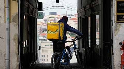 A Glovo delivery rider stops at an alley in Lisbon. The company has been fined by the European Commission for €106 million.
