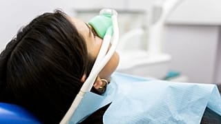 Una mujer inhala óxido nitroso en una consulta médica.