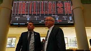 Δύο άνδρες στέκονται κάτω από έναν ηλεκτρονικό πίνακα που δείχνει τις τιμές των μετοχών στο Χρηματιστήριο Αξιών της Δαμασκού, 2 Ιουνίου 2025