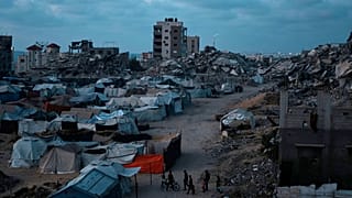Palestinians displaced by the Israeli air and ground offensive on the Gaza Strip, walk on an area at a makeshift tent camp during the dusk in Gaza City, 2 June 2025