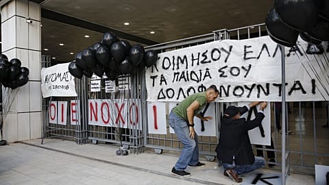 Relatives of victims of the deadly fire in Mati put up banners and black balloons outside the Athens Court of Appeal, on the day of the announcement of the court's decision